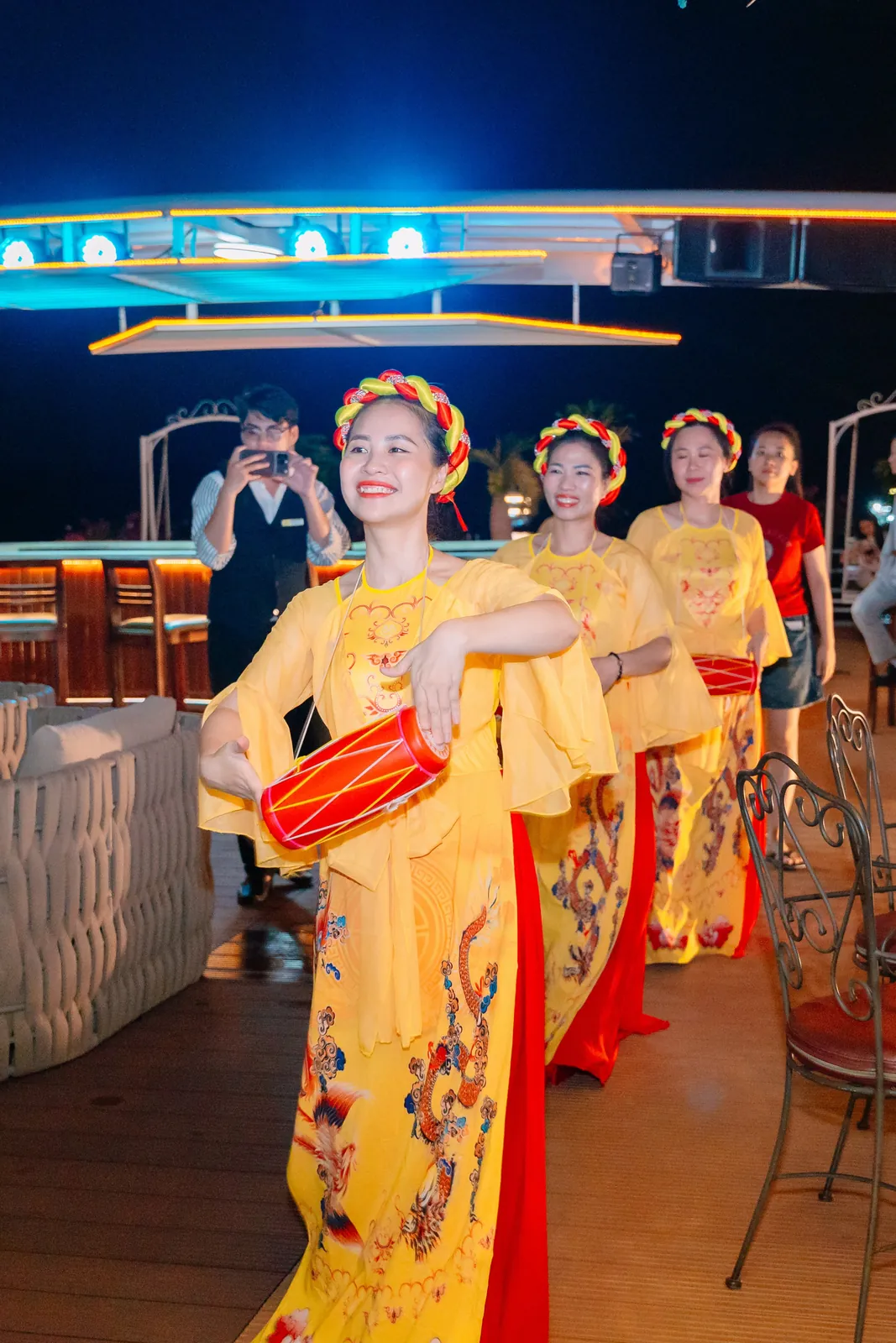 Ba nữ nghệ sĩ trong trang phục áo tứ thân vàng đỏ biểu diễn múa trống cơm trên du thuyền Hạ Long Princess