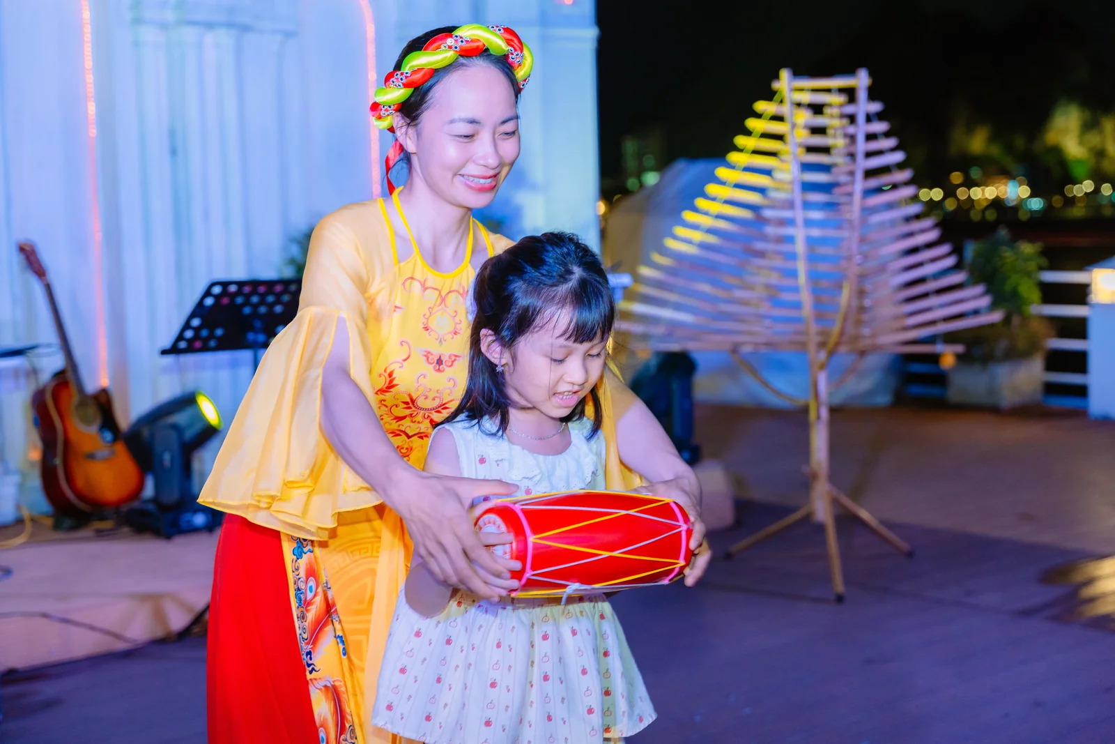 Nghệ sĩ hướng dẫn một bé gái đánh trống cơm trong minishow văn hoá dân gian trên du thuyền Hạ Long Princess