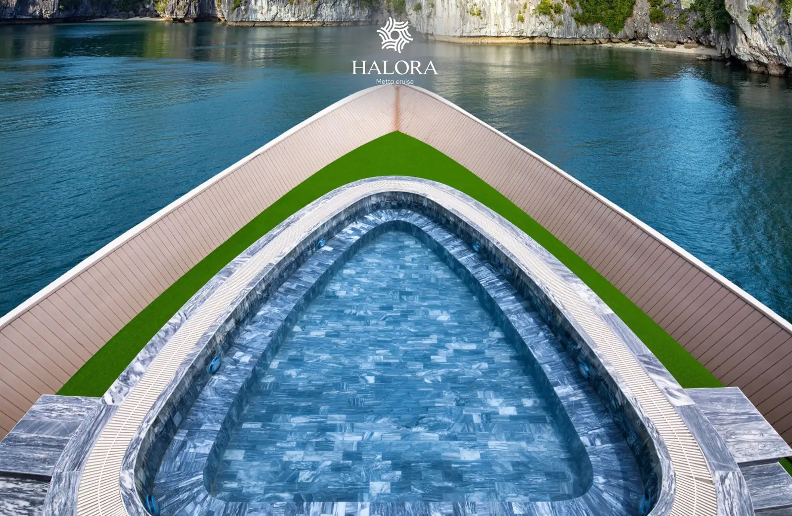 Bể sục jacuzzi hình giọt nước ốp đá vân xanh nằm nổi bật giữa sàn cỏ nhân tạo trên boong mũi tàu, nhìn từ trên cao.