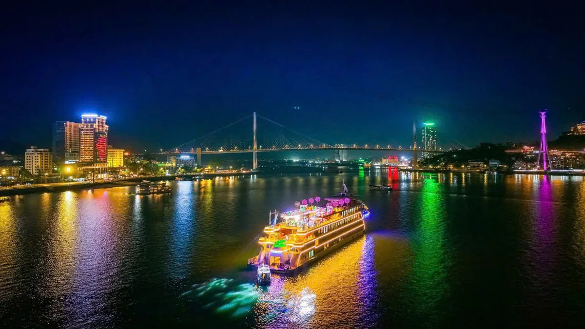Du thuyền Luna Halong Cruise thắp đèn lướt qua cây cầu và bờ thành phố Hạ Long về đêm