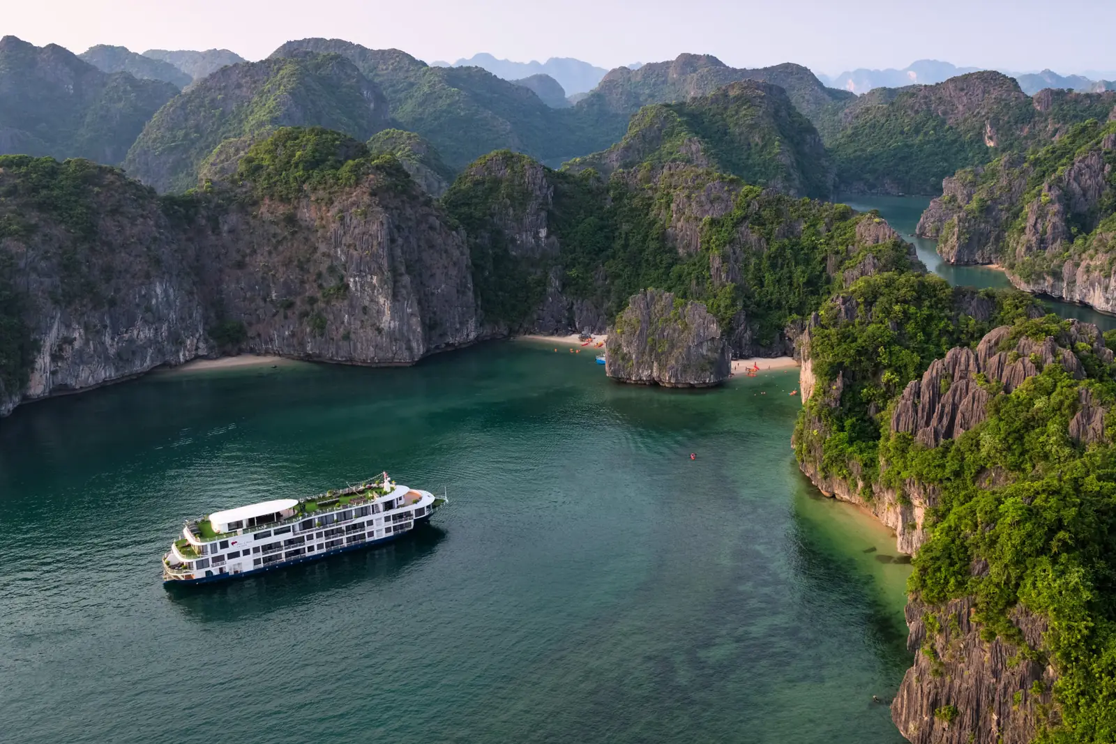Du thuyền Mon Chéri 1 neo gần bãi biển hoang sơ giữa núi đá vôi, khách chèo kayak gần bờ