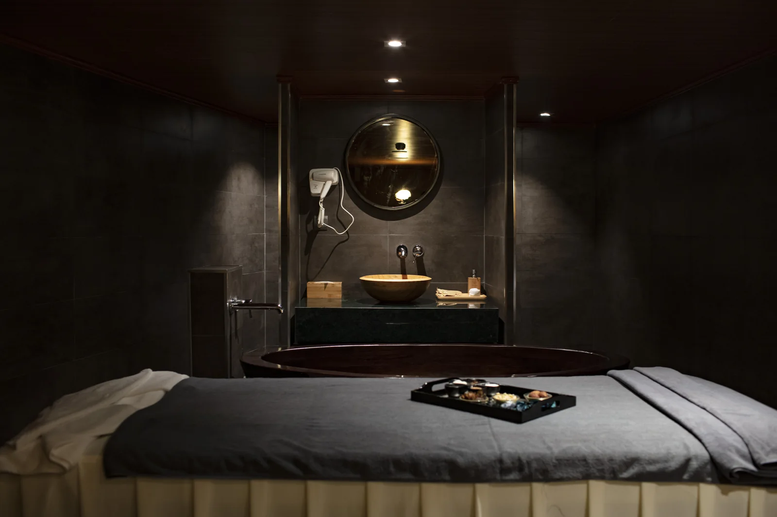 Phòng trị liệu tại Akoya Spa với giường massage, khay trà và bồn tắm gỗ phía sau, du thuyền Scarlet Pearl
