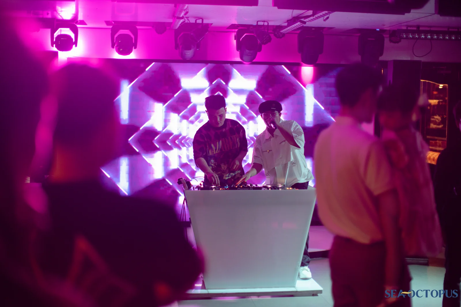 DJ chơi nhạc sôi động dưới ánh đèn neon hồng buổi tối